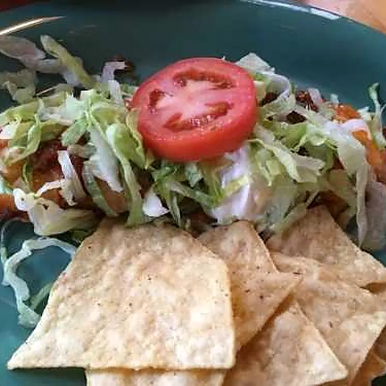 A tostada crisp on a teal plate with chips